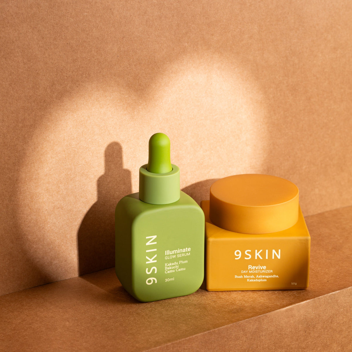 Green skincare dropper bottle and orange jar with '9SKIN' branding on a brown background