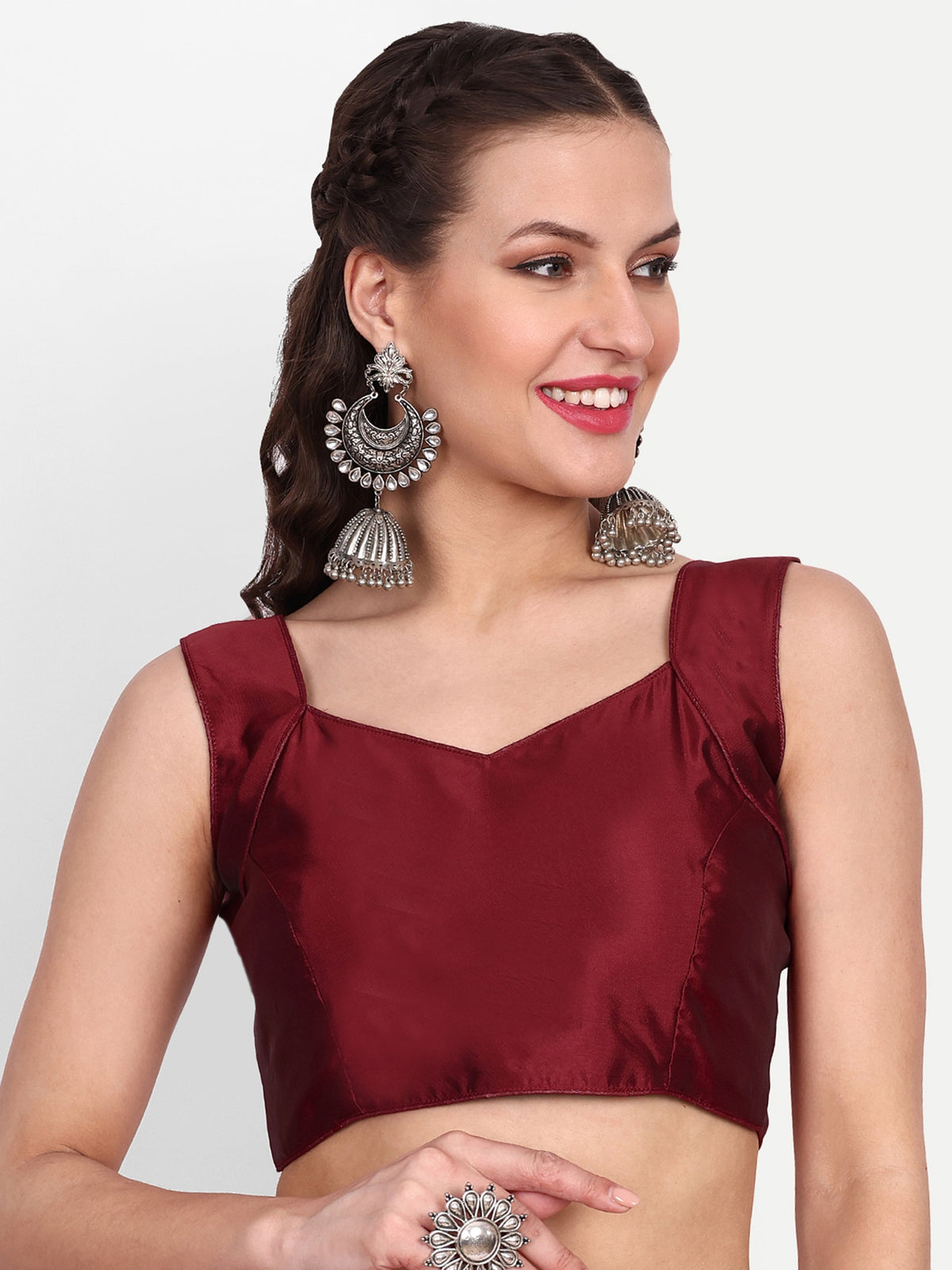 Woman wearing a maroon blouse with silver earrings on a white background