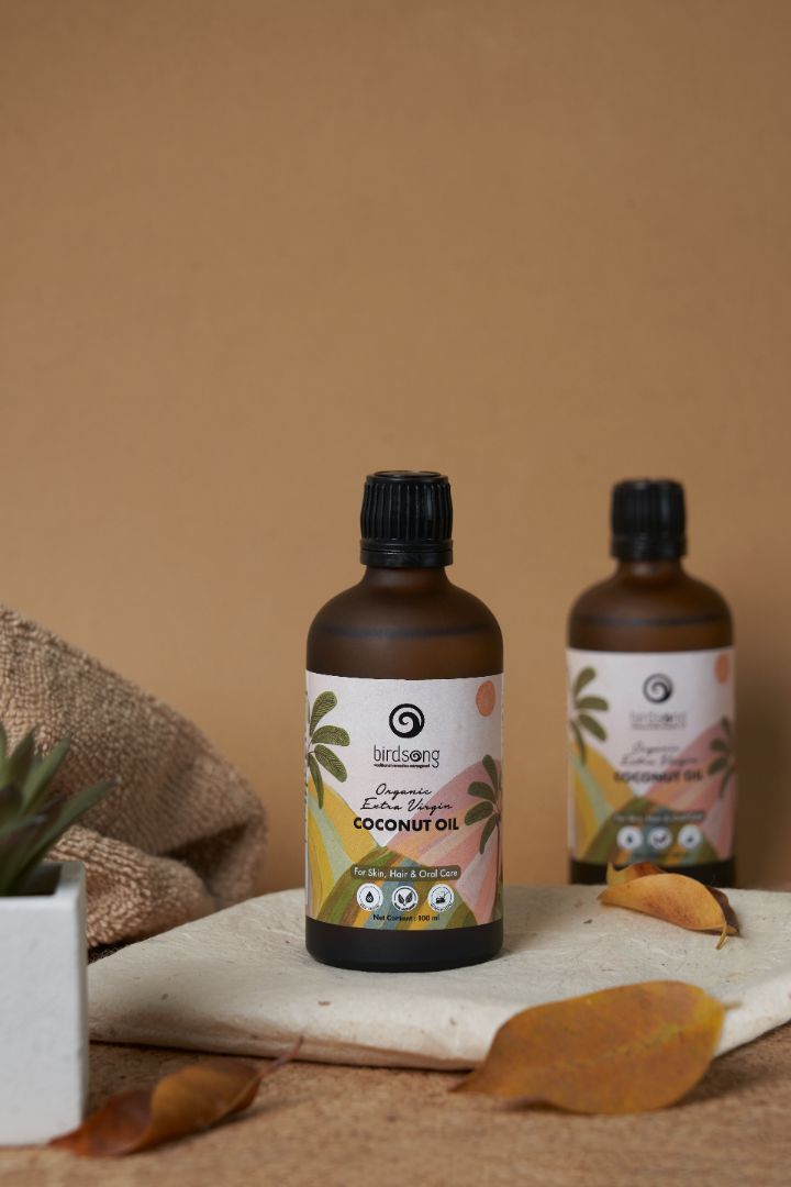 Two bottles of coconut oil on a wooden surface with a beige background