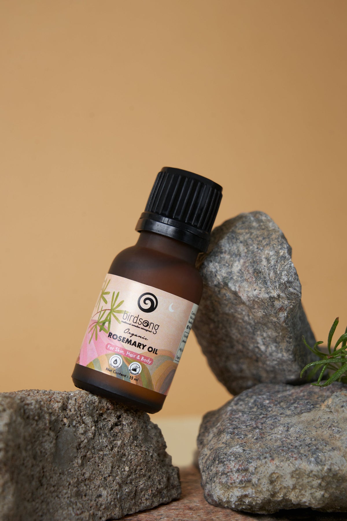 Bottle of Rosemary Oil on a rock with a natural background