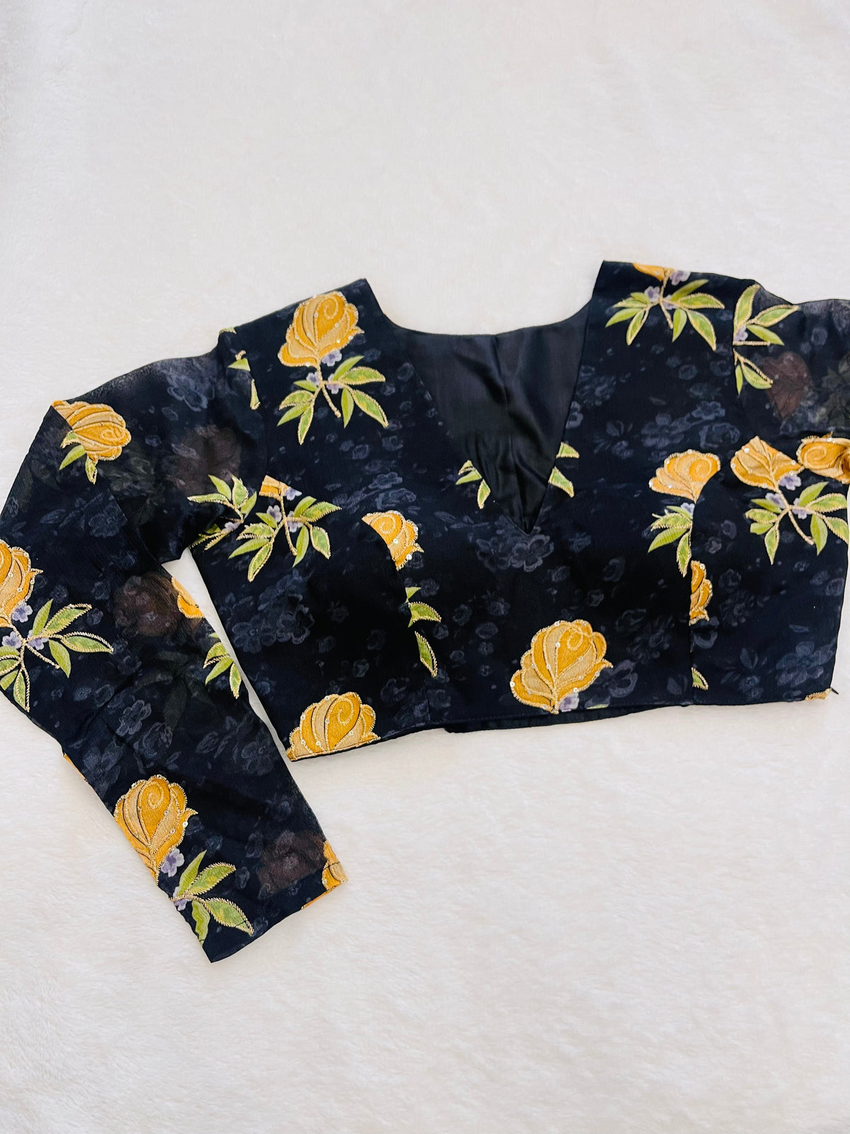 Black blouse with yellow floral patterns on a white background