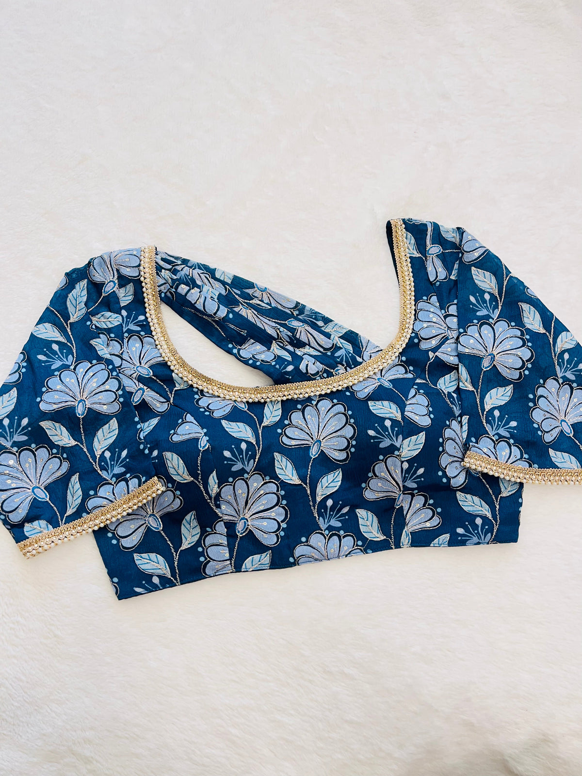 Blue floral blouse with beige trim on a white background