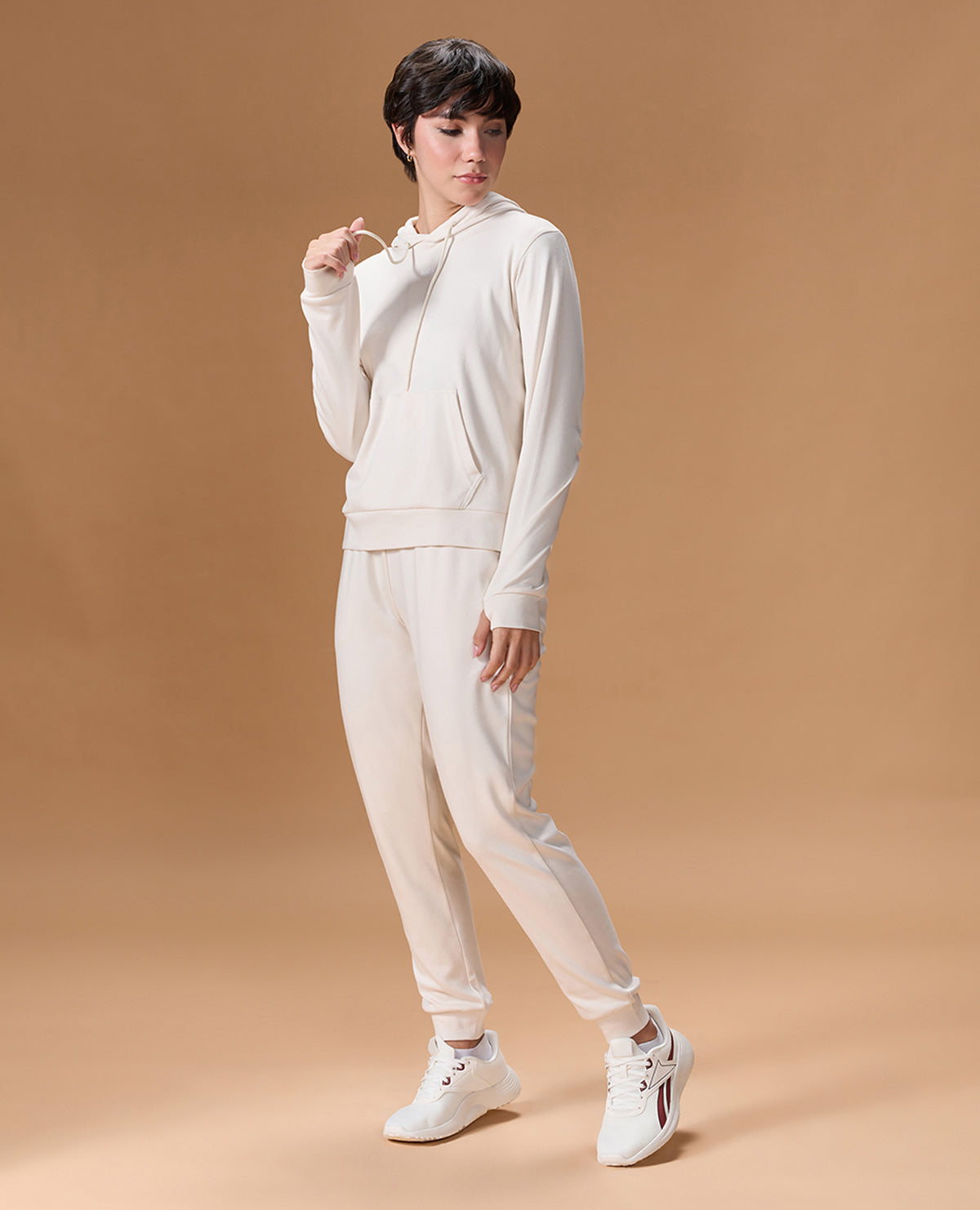 Woman wearing a white tracksuit on a beige background