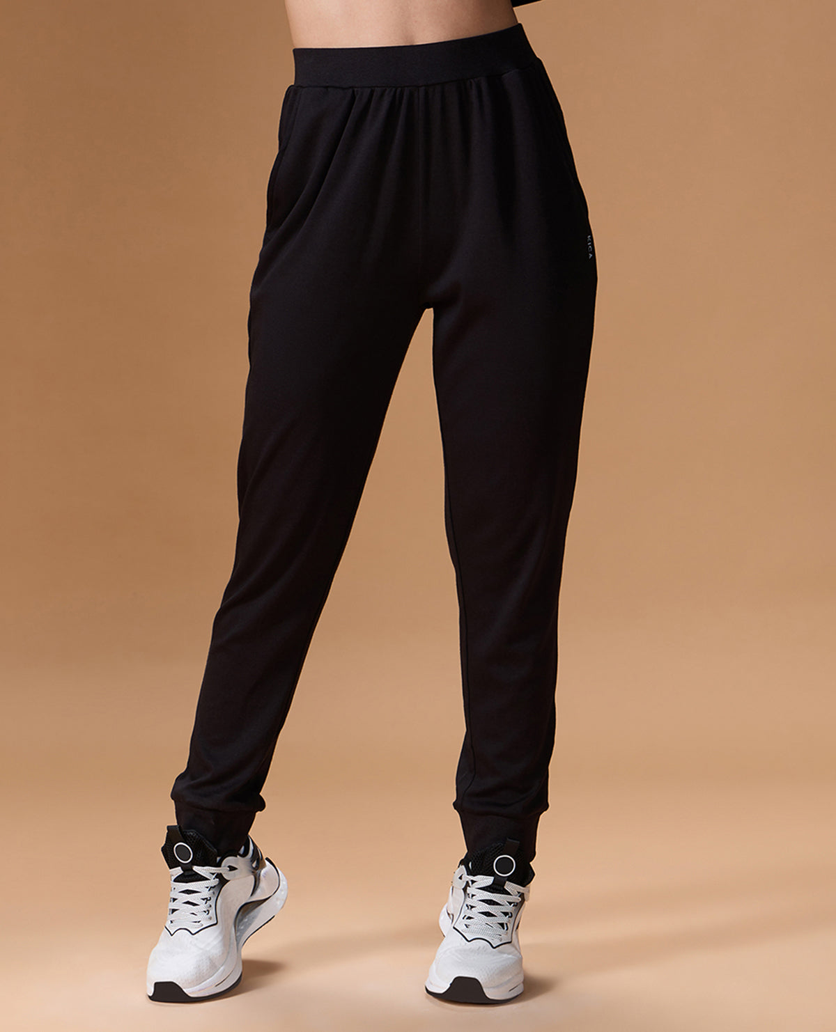 Black jogger pants worn by a person on a beige background