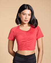 Woman wearing a red crop top against a beige background