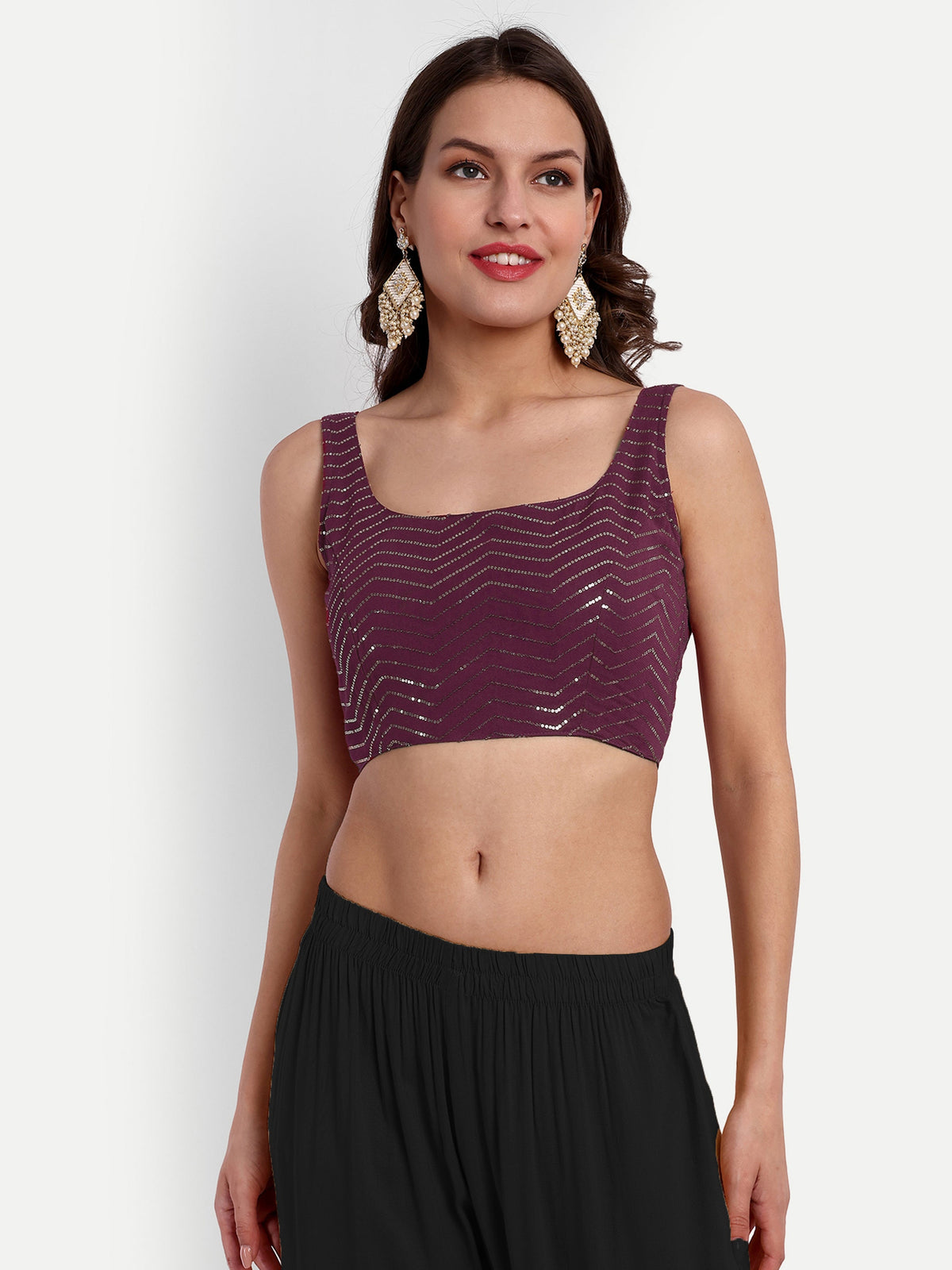 Woman wearing a purple sequined top and black pants on a white background