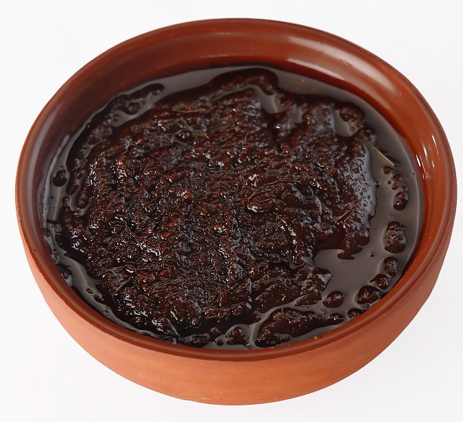 Dark brown jam in a terracotta bowl on a white background