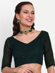 Woman wearing a dark green blouse with sheer sleeves against a white background
