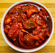 Spicy red curry in a white bowl on a wooden surface