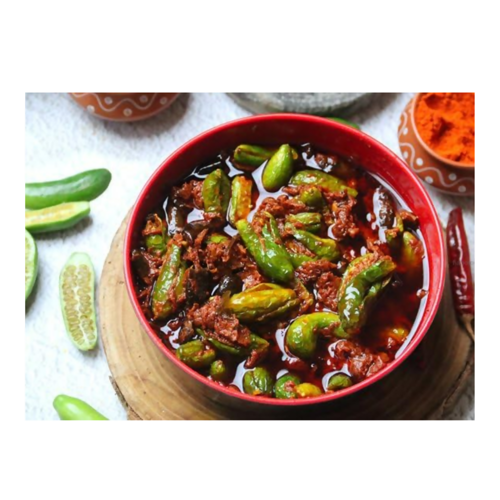 Bowl of green chili peppers in a red sauce on a white background