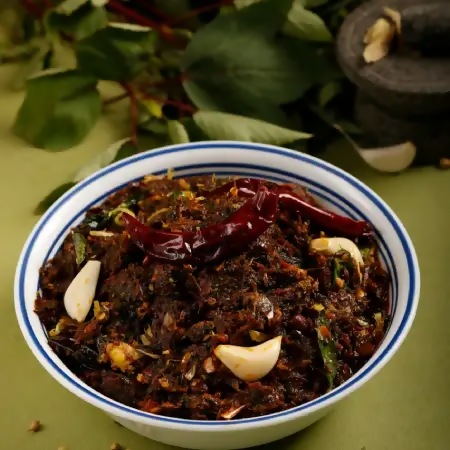 Spicy dish with red peppers and garlic in a white bowl with blue rim on a green background