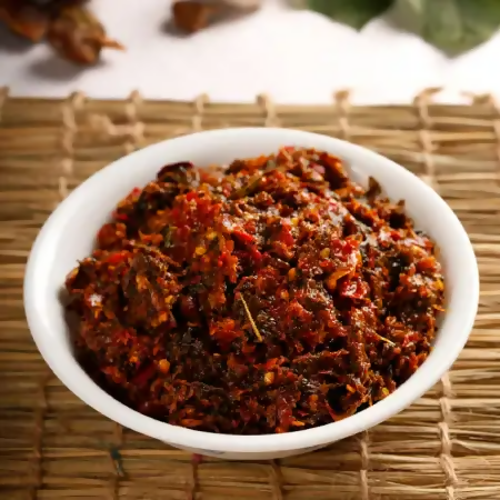 Spicy red pepper flakes in a white bowl on a woven mat