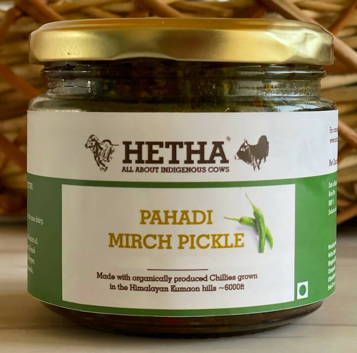 Jar of Hetha Pahadi Mirch Pickle with a gold lid on a wooden background