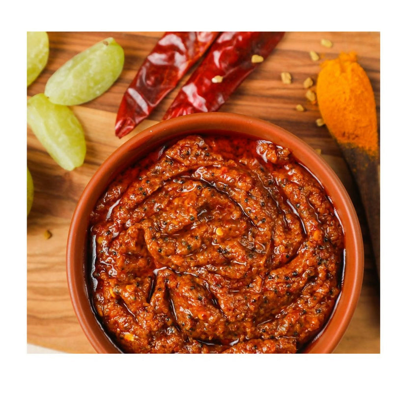 Bowl of red chutney on a wooden board with spices