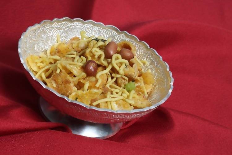 Noodles with grapes in a decorative bowl on a red fabric background