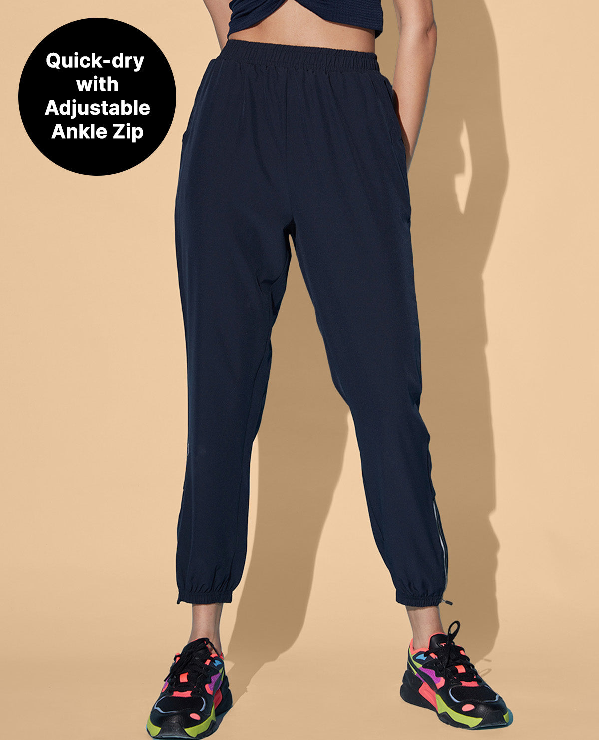 Person wearing navy jogger pants with text 'Quick-dry with Adjustable Ankle Zip' on a beige background