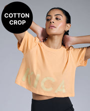 Woman wearing a peach-colored 'Kica' crop top with a gray background