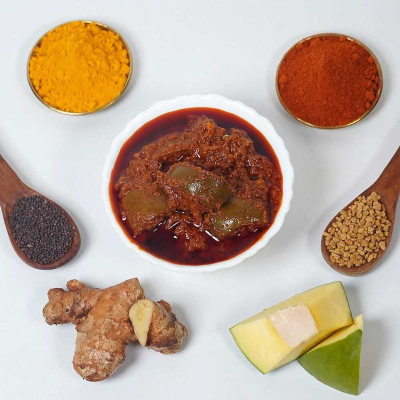 Spices and ingredients including a bowl of red paste, turmeric, ginger, and other seasonings on a white background.