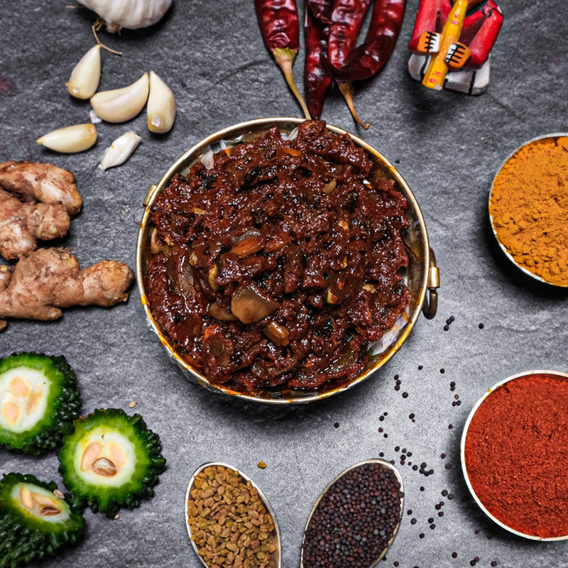 Spicy chili paste with ingredients like chilies, garlic, ginger, and spices on a dark surface.
