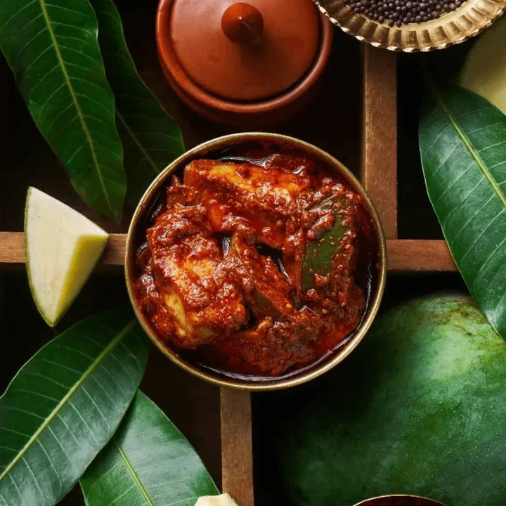 Bowl of curry with green leaves and a piece of fruit on a wooden tray