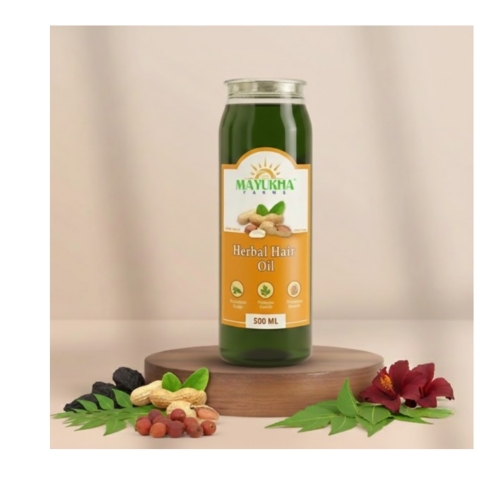 Bottle of Mayurka Herbal Hair Oil on a wooden platform with natural ingredients and flowers.