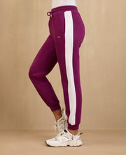 Purple jogger pants with a white stripe on a beige background
