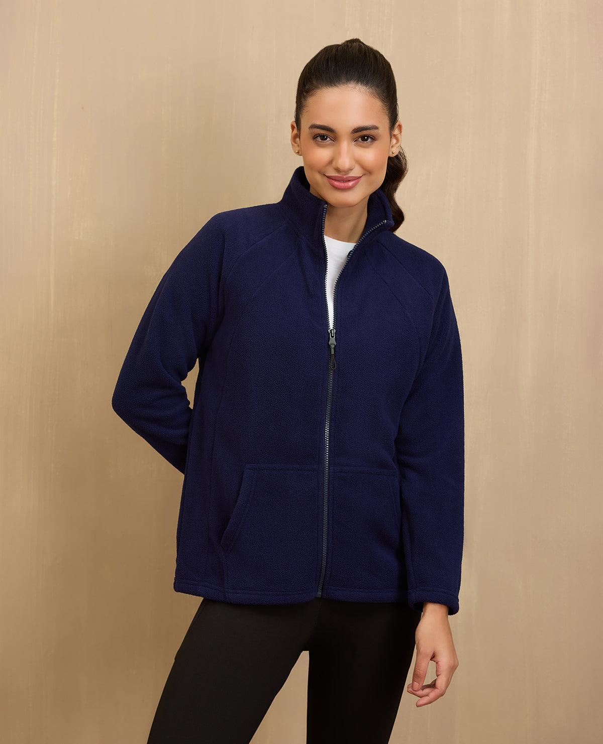 Woman wearing a navy blue jacket against a beige background