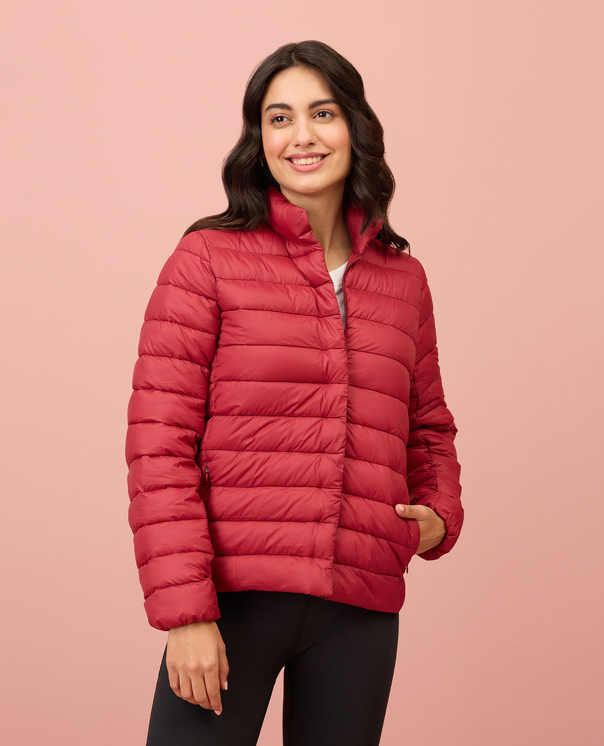 Woman wearing a red puffer jacket on a pink background