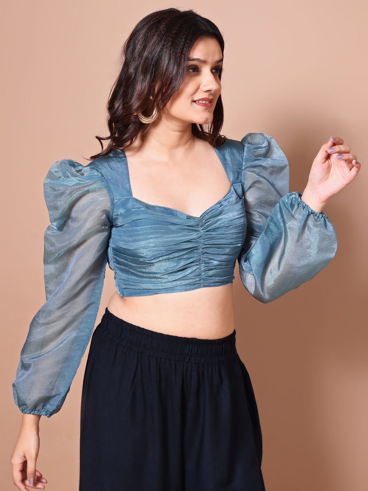 Woman wearing a blue blouse with puffed sleeves against a beige background