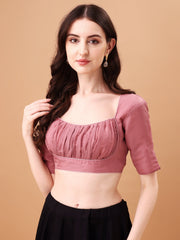 Woman wearing a mauve blouse with black pants against a beige background