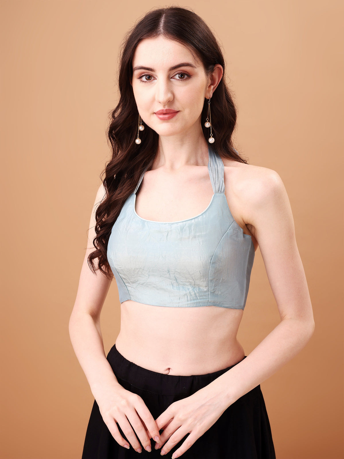 Woman wearing a light blue top and black pants against a beige background