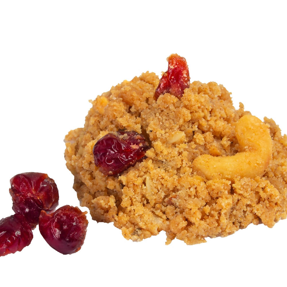 Crumbed food item with cranberries and a cashew on a white background
