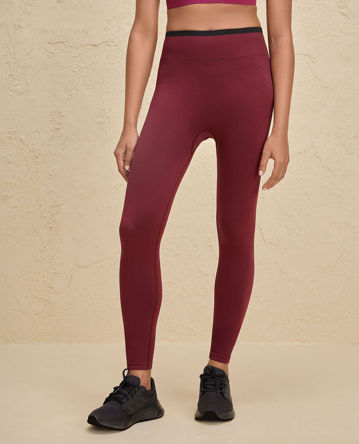 Maroon leggings worn by a person on a beige background