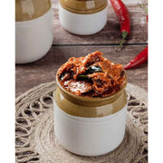 Jar of red curry paste on a wooden surface with red peppers.