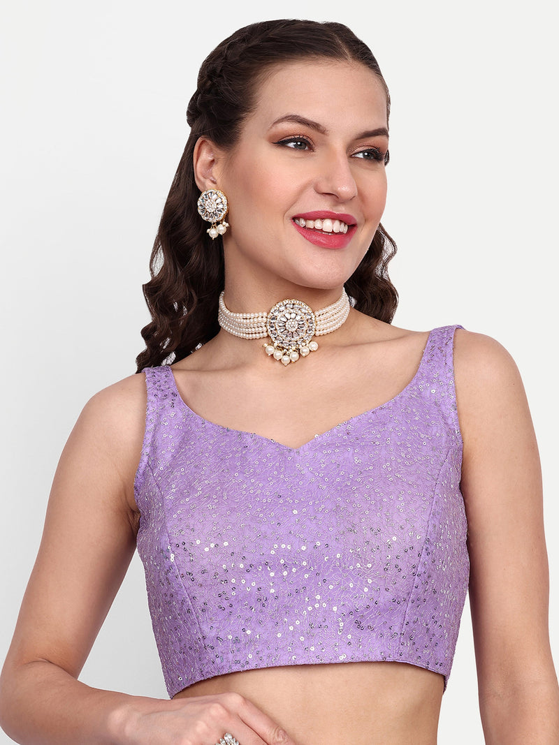 Woman wearing a purple sequined top with jewelry on a white background