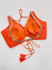 Orange bikini top with embellishments on a light gray background