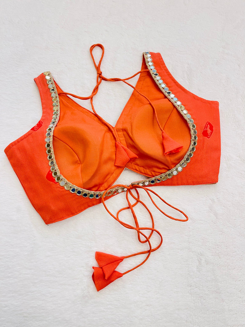 Orange bikini top with embellishments on a light gray background