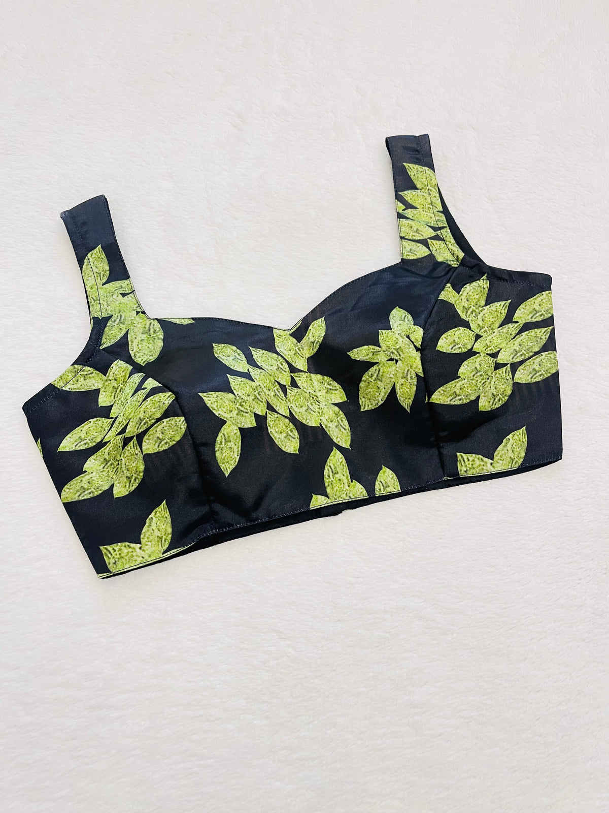 Black bikini top with green leaf pattern on a light gray background