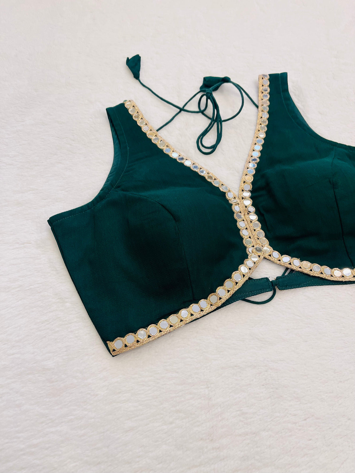 Green bikini top with pearl trim on a light gray background