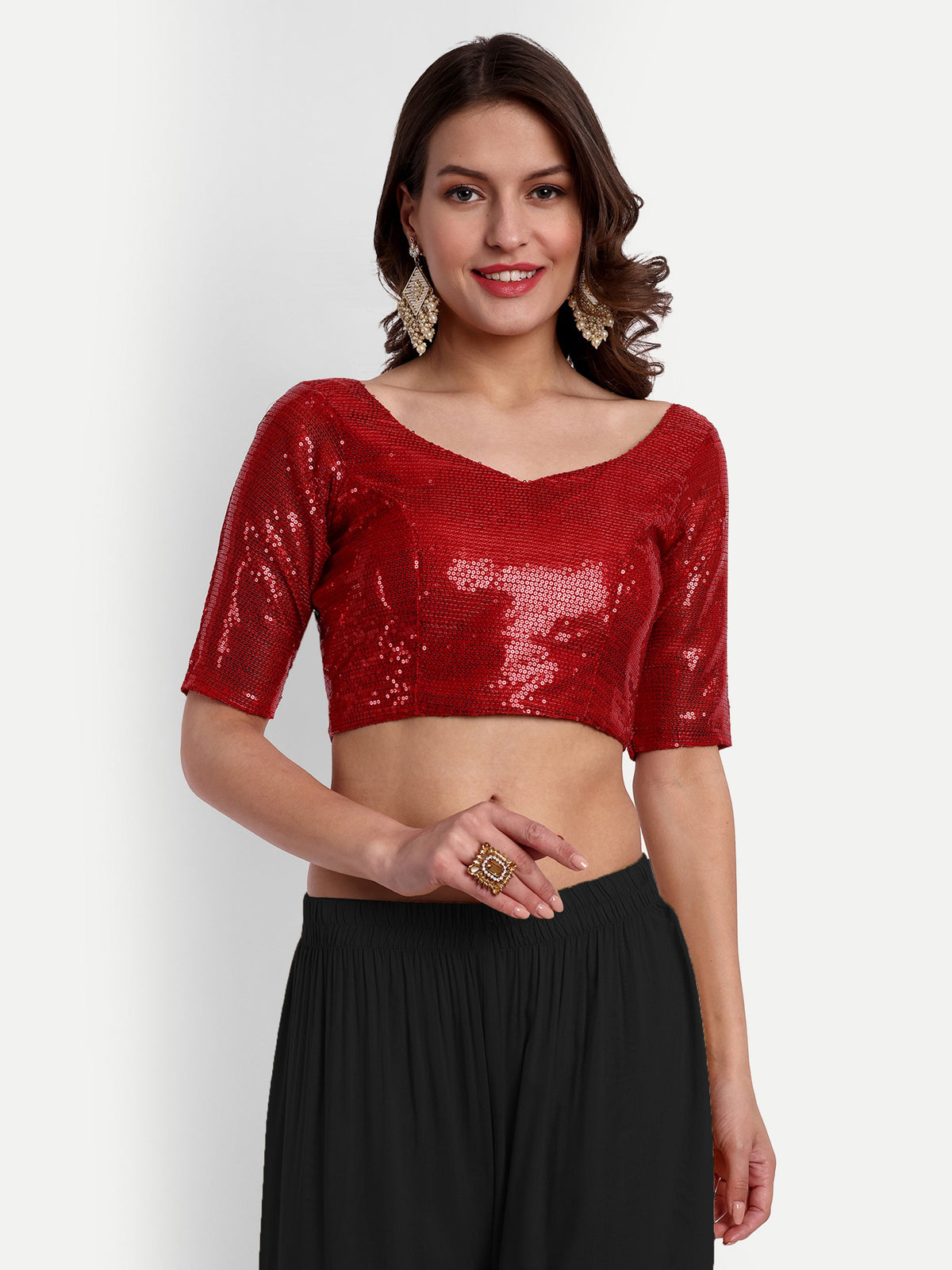 Woman wearing a red sequin top and black pants on a white background