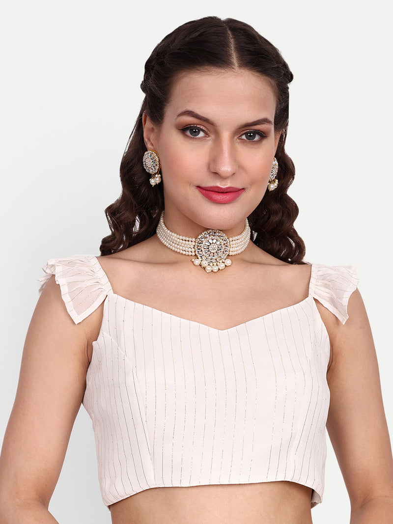 Woman wearing a white blouse with ruffled sleeves and a necklace on a light gray background