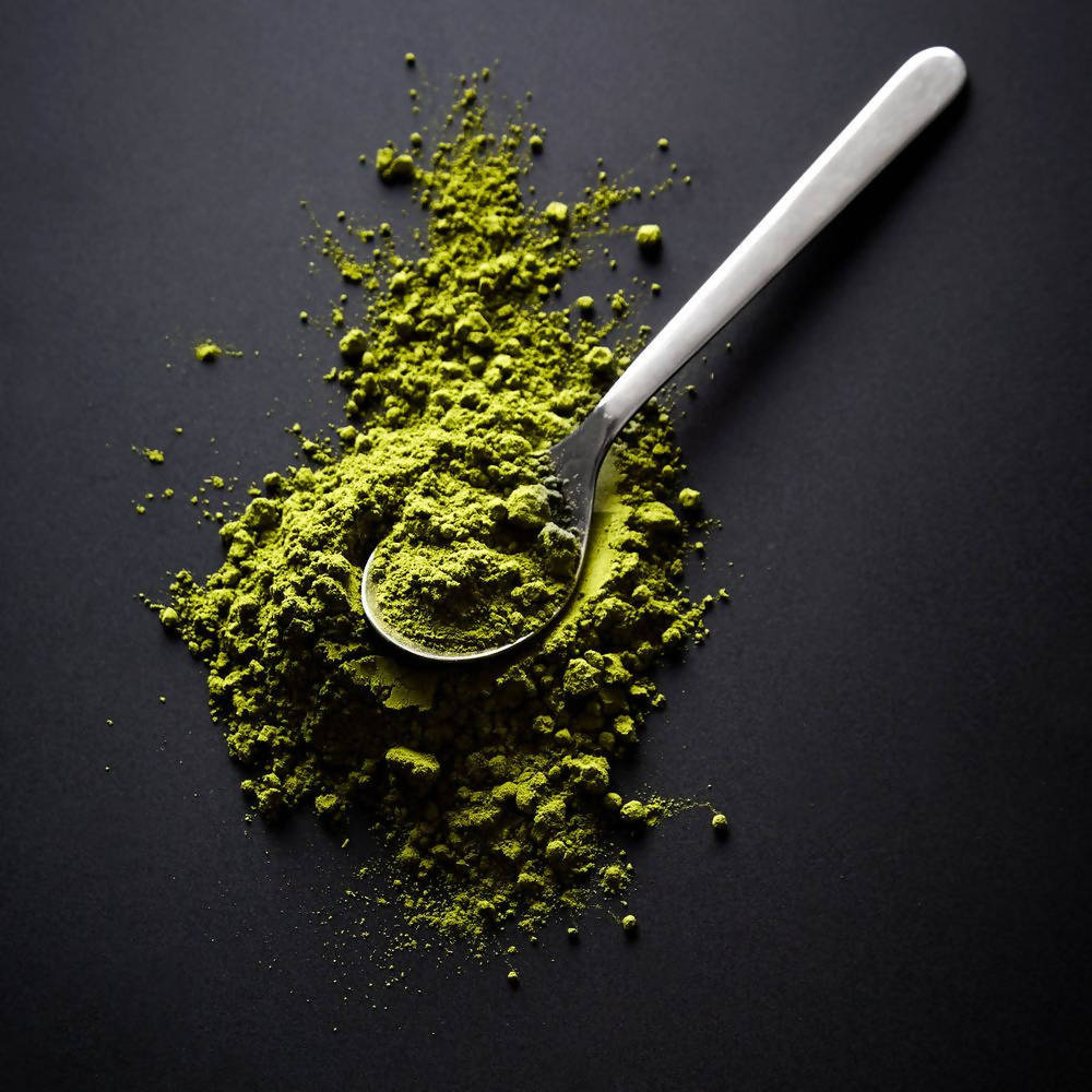 Green powder with a spoon on a black background