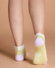 Yellow ankle socks with white accents worn by a person on a beige background