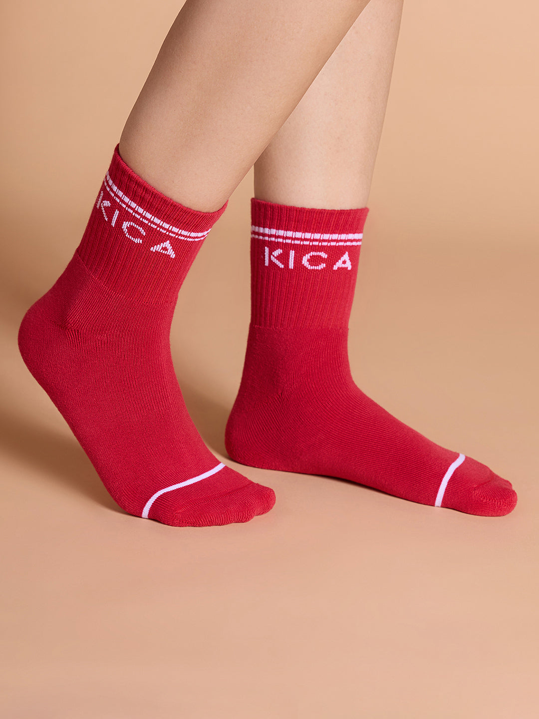 Red socks with 'KICA' branding on a beige background