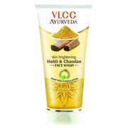 A plastic tube of VLCC Ayurveda skin brightening face wash with Haldi & Chandan. The packaging is chrome yellow with an illustration of turmeric and sandalwood and text detailing the product name and benefits.