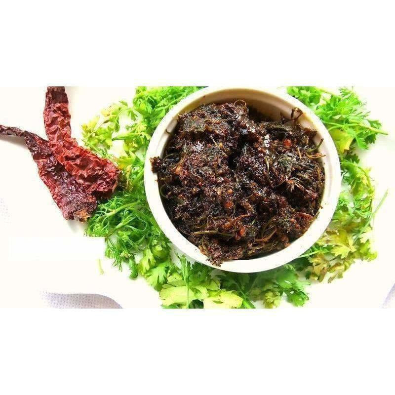 Dried insects in a bowl surrounded by green leaves on a white background