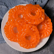 Orange jelly candies on a white plate with a gray background