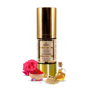 Skincare product with gold cap and label, accompanied by a pink rose, bowl of spices, and small bottle on a white background.
