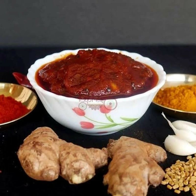 Bowl of red sauce with ginger, garlic, and other spices on a dark surface