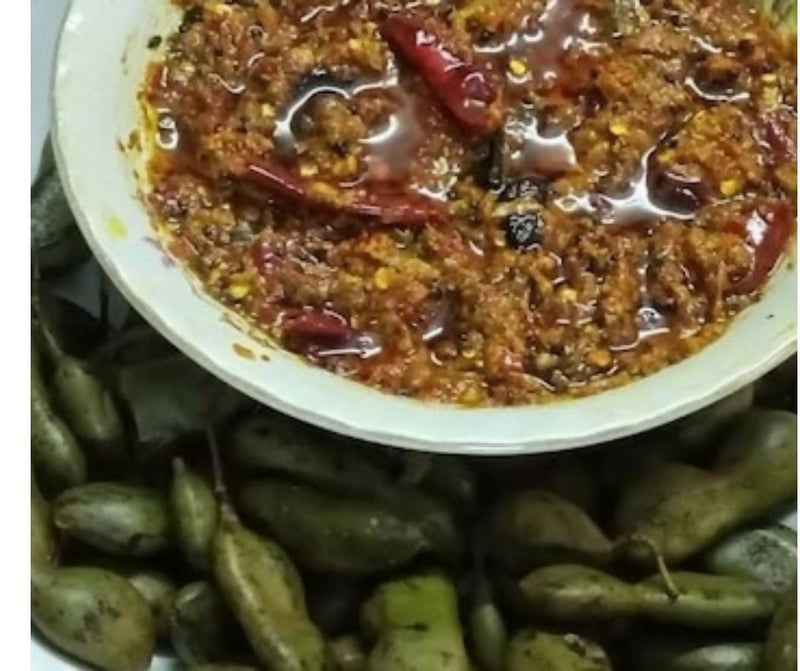 Spicy red sauce in a white bowl with green beans on a dark background